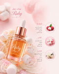Ruby perfume oil in a clear glass dropper bottle with a rose gold cap, surrounded by pink marshmallows and soft pink background elements. Arabic text and three circular ingredient callouts are printed on the right side of the image.